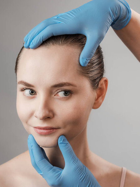 Косметические процедуры для молодого красивого женского лица, рука врача в перчатках касаются лица женщины, изолированной на белом. Уход за кожей, косметологические процедуры, воск для тела, норковая ресница, уход за бровями, постоянный