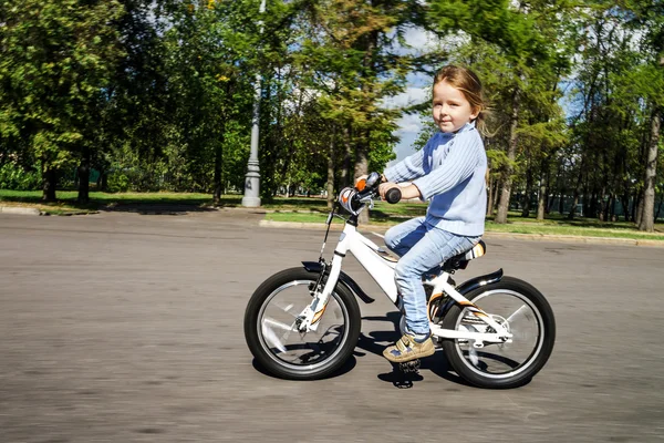 Cute little girl riding fast by bicycle — Stock Photo, Image