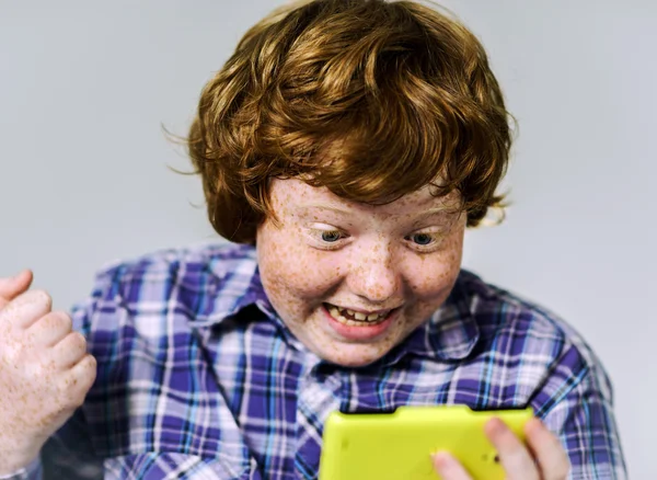 Komiska fräknig rödhårig pojke med mobiltelefon — Stockfoto