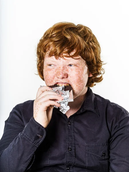 Happy red-haired boy with chocolate bar — Stock Photo, Image