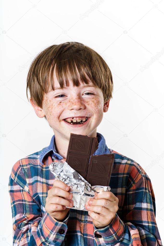 Happy red-haired boy with chocolate bar
