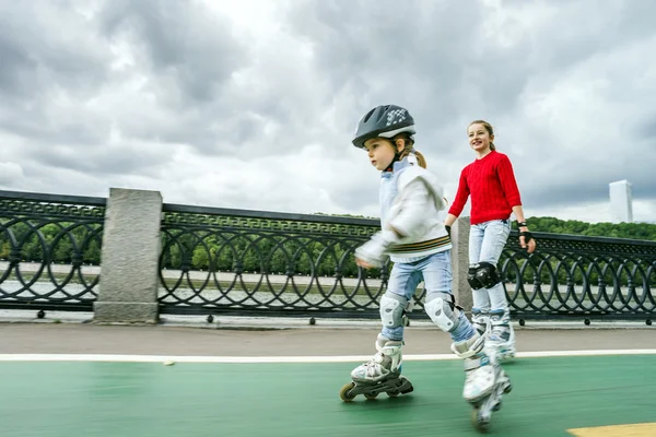 Cute little girl learning rollerskating with her sister — Stock Photo, Image