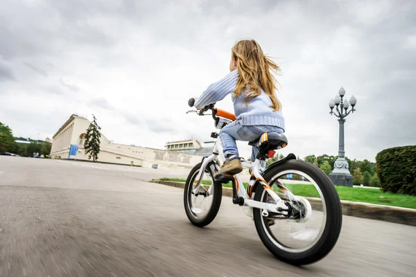 Cute little girl riding fast by bicycle — Stock Photo, Image