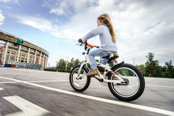 Cute little girl riding fast by bicycle — Stock Photo, Image