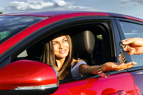 Jovem mulher tomando chaves de carro novo — Fotografia de Stock