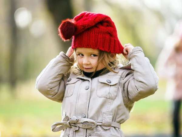 Cute little girl on playground in autumnal park — Stock Photo, Image
