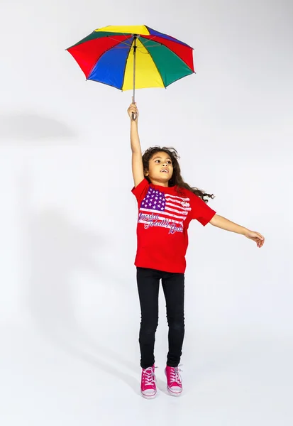 Cute little smiling afro-american girl jumping with colorful umb — Stock Photo, Image