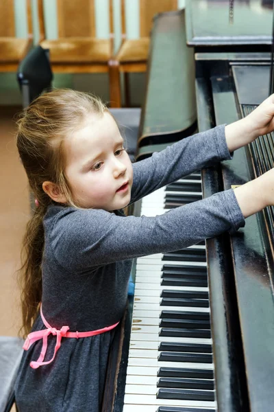 Cute little girl playing grand piano — Stock Photo, Image