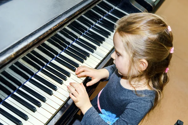 Niedliches kleines Mädchen spielt Flügel — Stockfoto