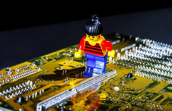 Homem em miniatura posando em uma placa-mãe de computador — Fotografia de Stock