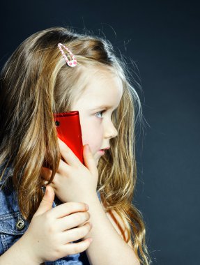 Yeni bir cep telefonu kullanarak sevimli küçük kız konuşuyor.