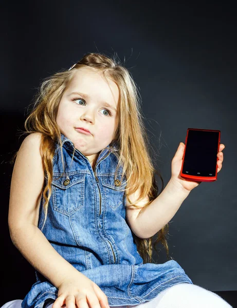 Linda niña mostrando la pantalla en blanco del teléfono inteligente moderno —  Fotos de Stock