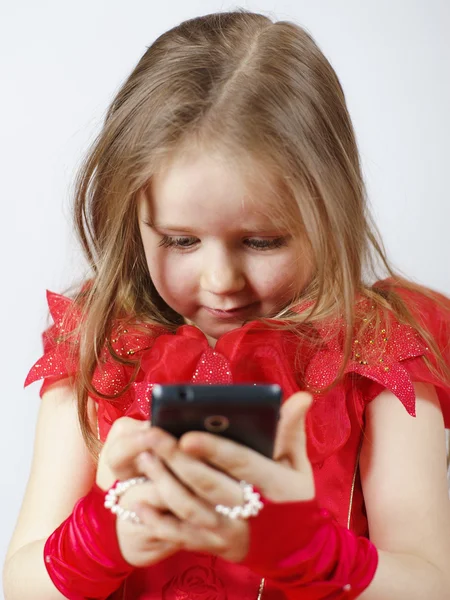 Menina bonito vestido com vestido de baile jogando com smartphone — Fotografia de Stock