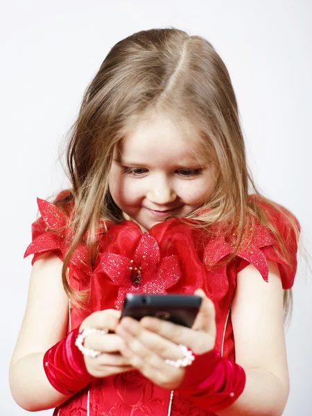 Schattig klein meisje gekleed in bal toga spelen met smartphone — Stockfoto