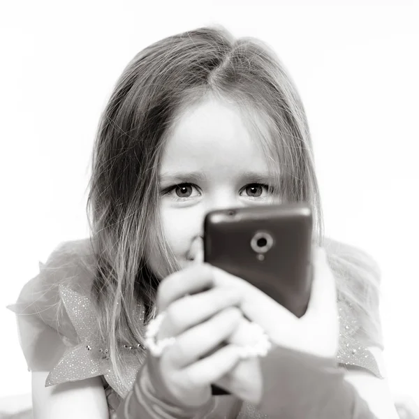 Cute little girl dressed in ball gown playing with smartphone — Stock Photo, Image