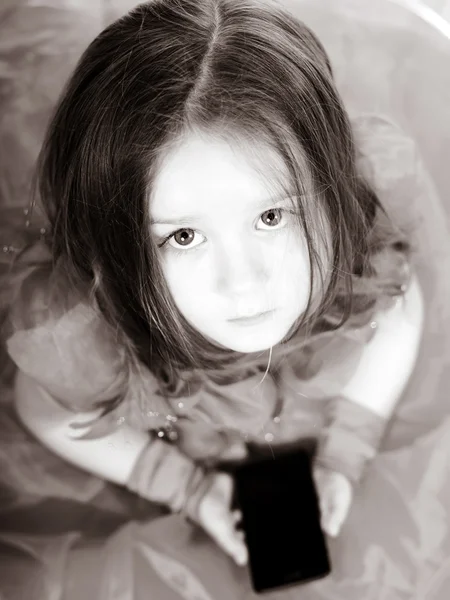 Cute little girl dressed in ball gown playing with smartphone — Stock Photo, Image