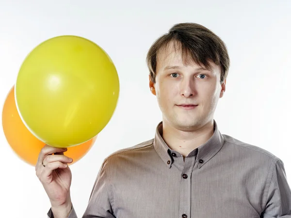 Young caucasian man holding yellow air balloons in his hand — Stock Photo, Image