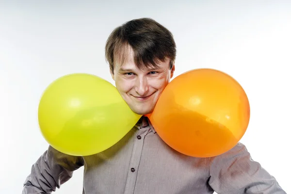 Young caucasian man holding yellow air balloons in his hand — Stock Photo, Image