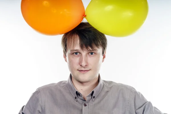 Young caucasian man holding yellow air balloons in his hand — Stock Photo, Image