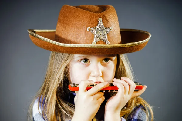 Милая маленькая девочка играет на губной гармошке — стоковое фото