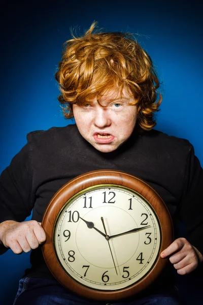 Expressive rousse adolescent garçon montrant le temps sur une grande horloge — Photo