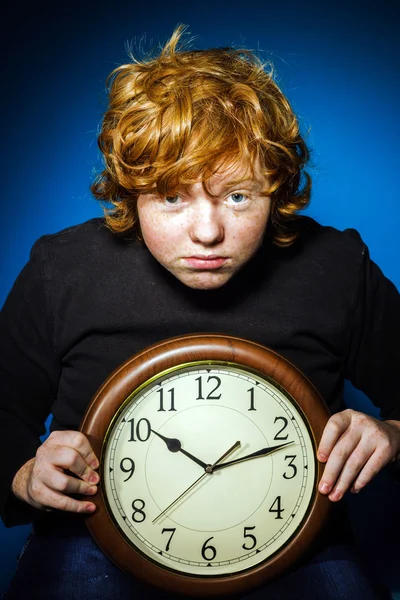 Expressive rousse adolescent garçon montrant le temps sur une grande horloge — Photo