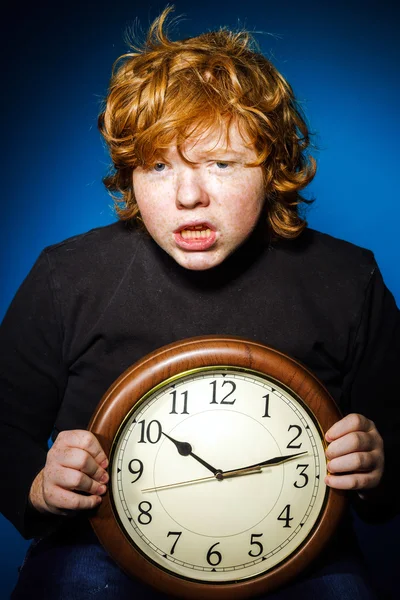 Expressive rousse adolescent garçon montrant le temps sur une grande horloge — Photo