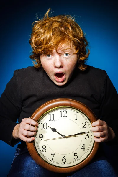 Εκφραστική κοκκινομάλλης έφηβου αγοριού που δείχνει την ώρα σε μεγάλο ρολόι — Φωτογραφία Αρχείου