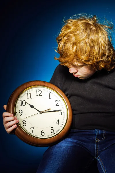 Expressive rousse adolescent garçon montrant le temps sur une grande horloge — Photo