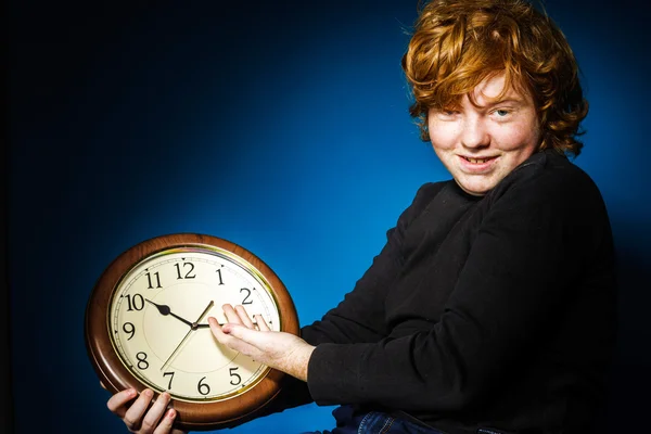 Expressive rousse adolescent garçon montrant le temps sur une grande horloge — Photo