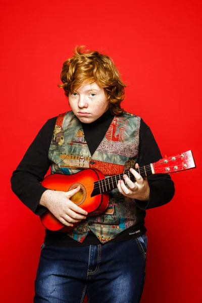 Red-hair funny teenage boy playing little guitar — Stock Photo, Image