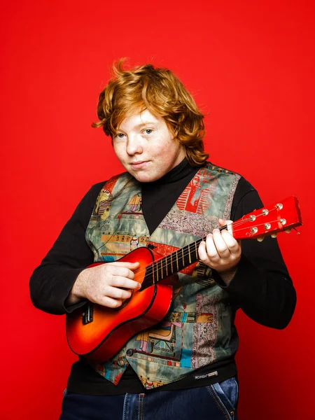 Red-hair funny teenage boy playing little guitar — Stock Photo, Image