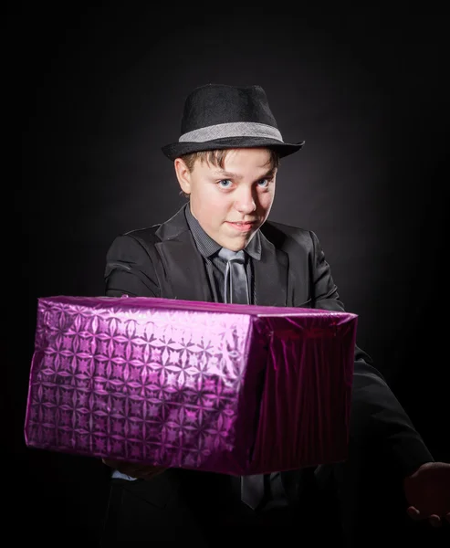 Expressive teenage boy holding box with gift — Stock Photo, Image
