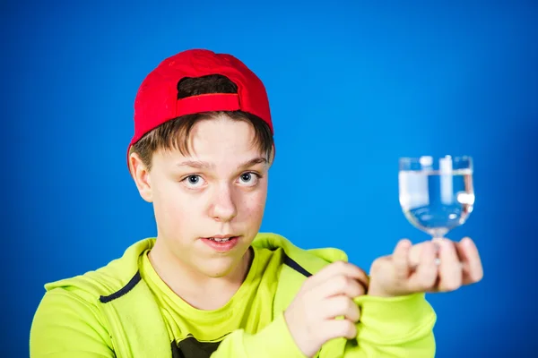 Rapaz adolescente expressivo posando com um copo de água — Fotografia de Stock