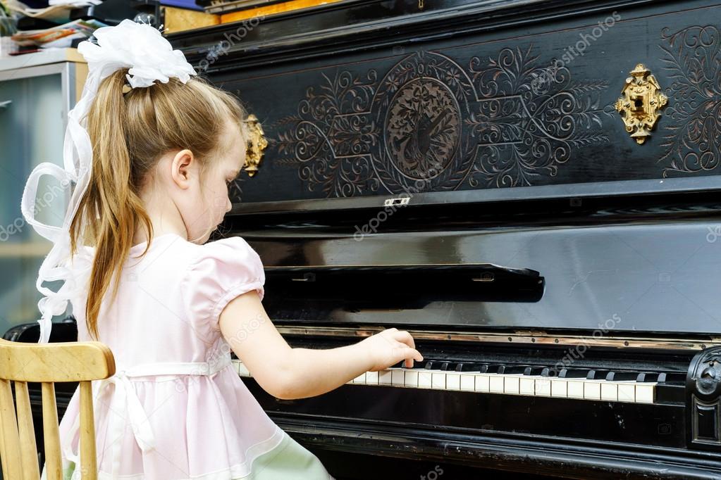 Cute little girl playing old piano