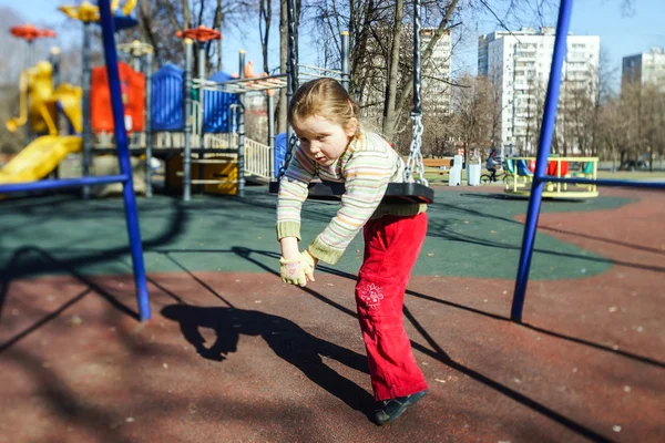 Cute little girl swinging seesaw on children playground — Stock Photo, Image