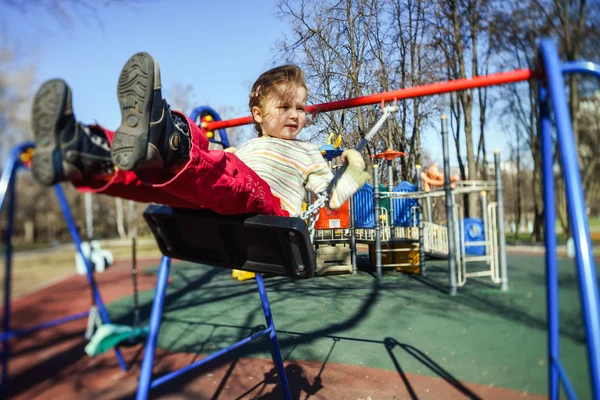 Carino bambina oscillante altalena sul parco giochi per bambini — Foto Stock