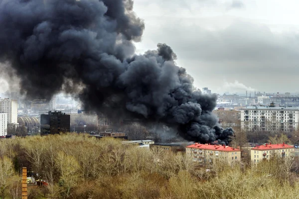 Columna de humo negro por encima de la chimenea en la ciudad — Foto de Stock