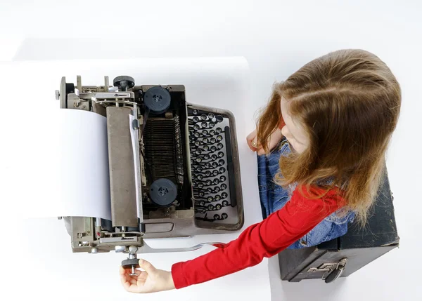 Linda niña escribiendo en el teclado de la máquina de escribir vintage —  Fotos de Stock