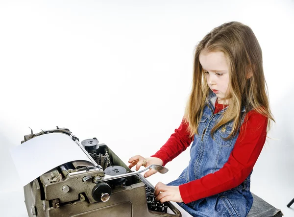 Милая маленькая девочка, печатающая на винтажной машинке — стоковое фото