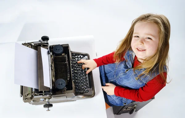 Cute little girl typing on vintage typewriter keyboard — Stock Photo, Image