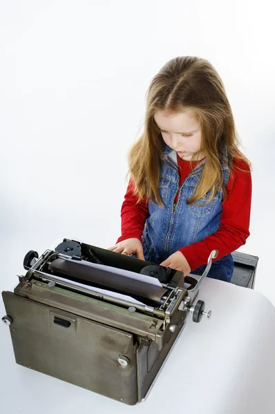 Cute little girl typing on vintage typewriter keyboard — Stock Photo, Image