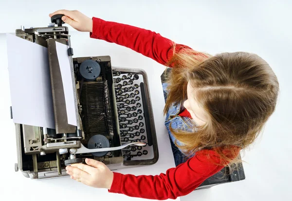 Cute little girl typing on vintage typewriter keyboard — Stock Photo, Image