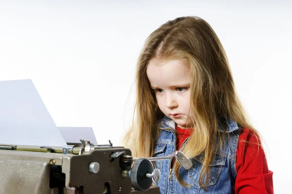 Niedliches kleines Mädchen tippt auf Vintage-Schreibmaschine-Tastatur — Stockfoto