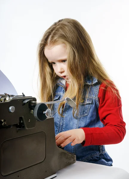 Милая маленькая девочка, печатающая на винтажной машинке — стоковое фото