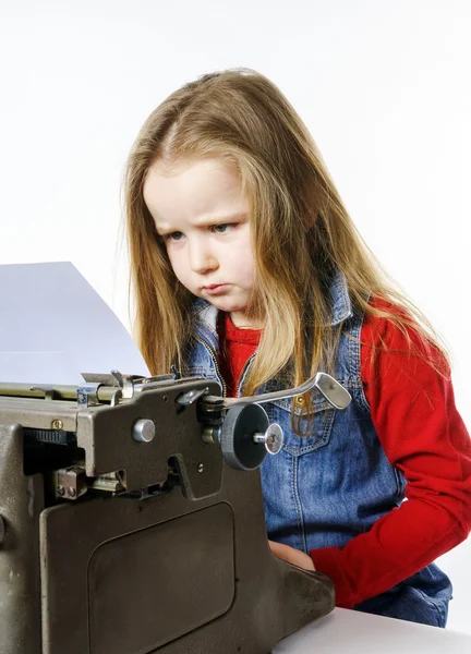 Niedliches kleines Mädchen tippt auf Vintage-Schreibmaschine-Tastatur — Stockfoto