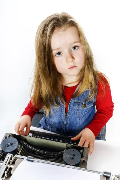 Linda niña escribiendo en el teclado de la máquina de escribir vintage —  Fotos de Stock