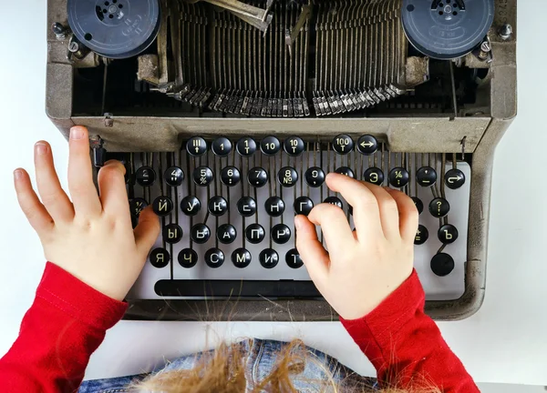 Cute little girl typing on vintage typewriter keyboard — Stock Photo, Image