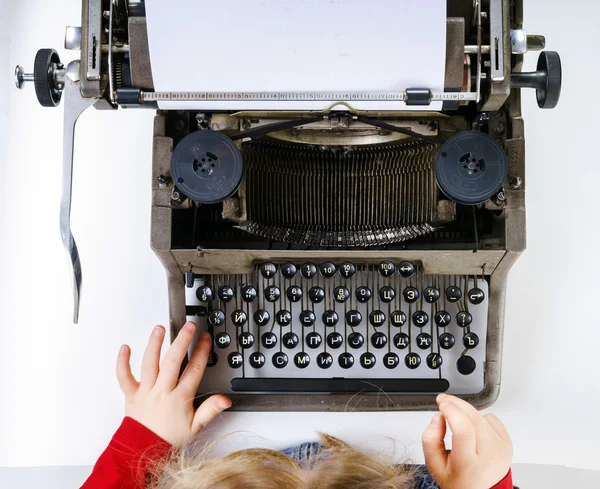 Cute little girl typing on vintage typewriter keyboard — Stock Photo, Image