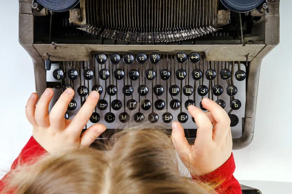 Cute little girl typing on vintage typewriter keyboard — Stock Photo, Image